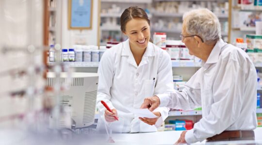 Pharmacist talking to elderly man in chemist. | Newsreel