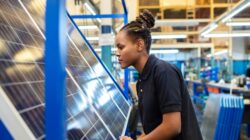 Worker inspecting a solar panel in a factory.