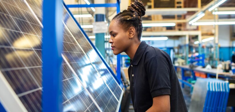 Worker inspecting a solar panel in a factory.