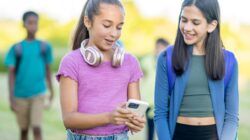 Teenagers looking at mobile phone. | Newsreel