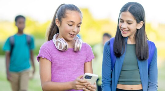 Teenagers looking at mobile phone. | Newsreel