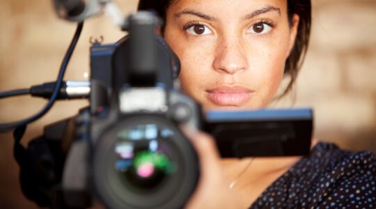 Woman behind film camera. | Newsreel