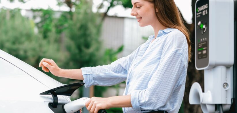 Woman charging electric vehicle. | Newsreel