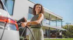 Woman charging electric car. | Newsreel