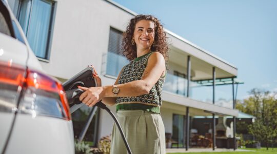 Woman charging electric car. | Newsreel