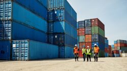 Workers at port with shipping containers. | Newsreel