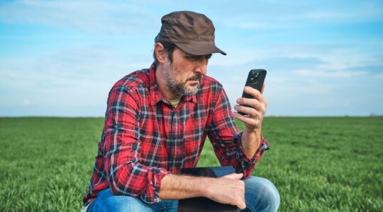 Farmer looking at smart phone in the field. | Newsreel