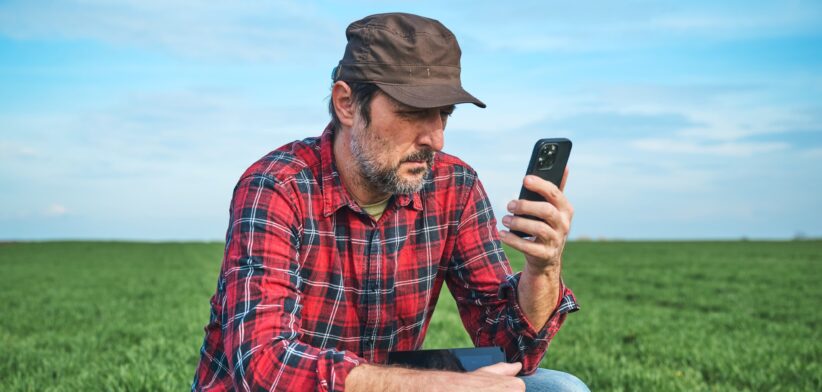 Farmer looking at smart phone in the field. | Newsreel