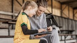 Young sports person and adult looking at computer. | Newsreel