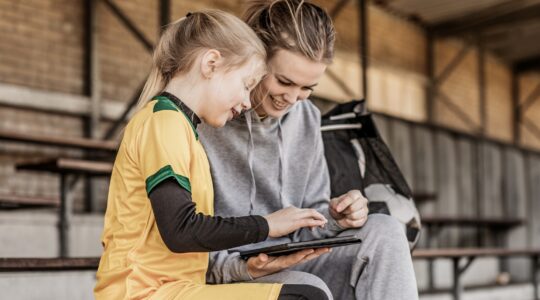 Young sports person and adult looking at computer. | Newsreel