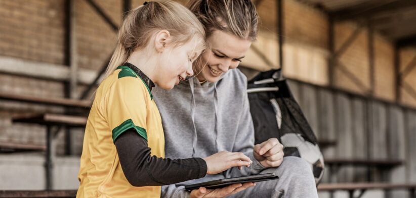 Young sports person and adult looking at computer. | Newsreel