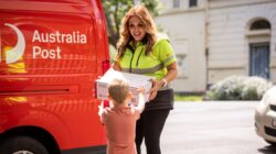 Australia Post delivery woman handing parcel to child.