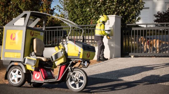 Australia Post postie delivering with dog safely contained.