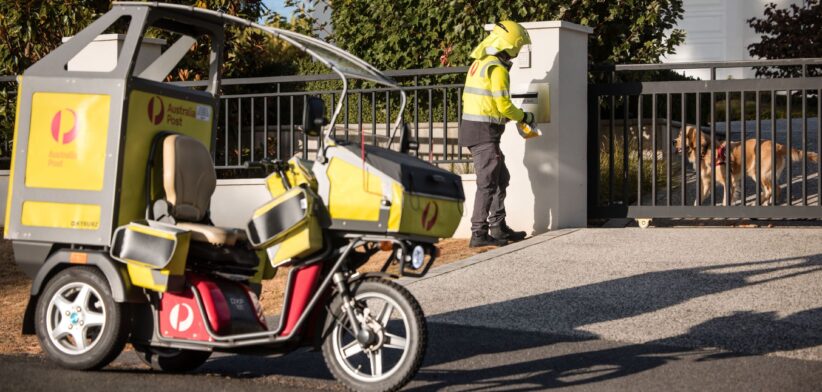 Australia Post postie delivering with dog safely contained.