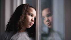 Sad girl looking out window. | Newsreel