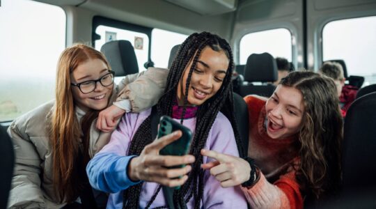 Teenagers looking at mobile phone. | Newsreel