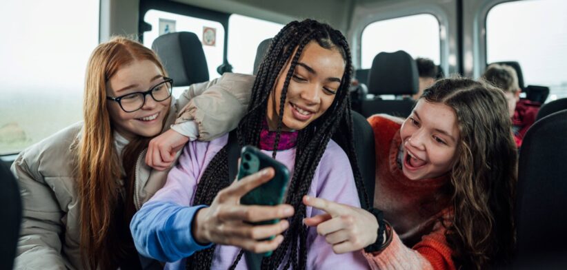 Teenagers looking at mobile phone. | Newsreel