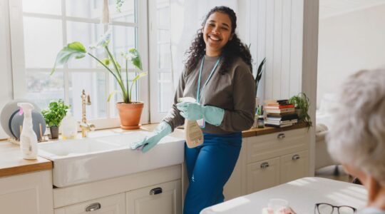 Woman helping older person with cleaning. | Newsreel