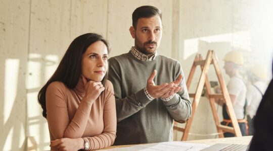 Couple talking to home builder. | Newsreel