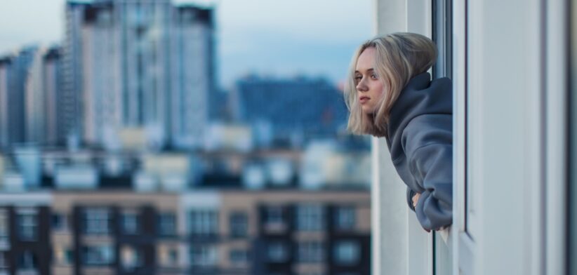 Young person looking our window of apartment. | Newsreel