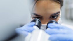 Woman looking through microscope. | Newsreel