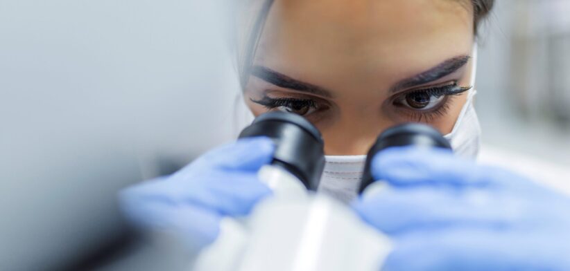 Woman looking through microscope. | Newsreel