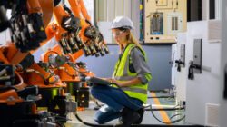 Woman with robots in factory. | Newsreel