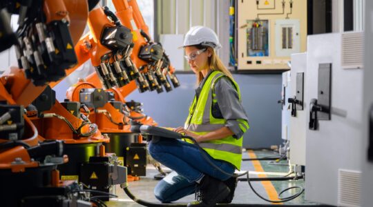 Woman with robots in factory. | Newsreel