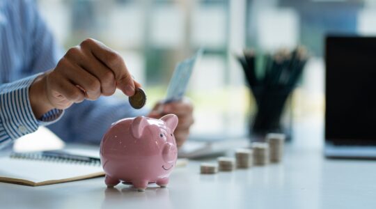 Person putting money in piggy bank. | Newsreel