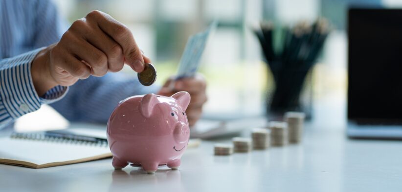 Person putting money in piggy bank. | Newsreel