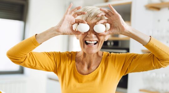 Woman holding eggs in front of eyes. | Newsreel