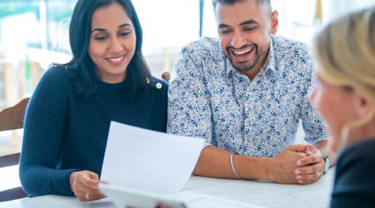 Couple looking at paperwork with business person. | Newsreel