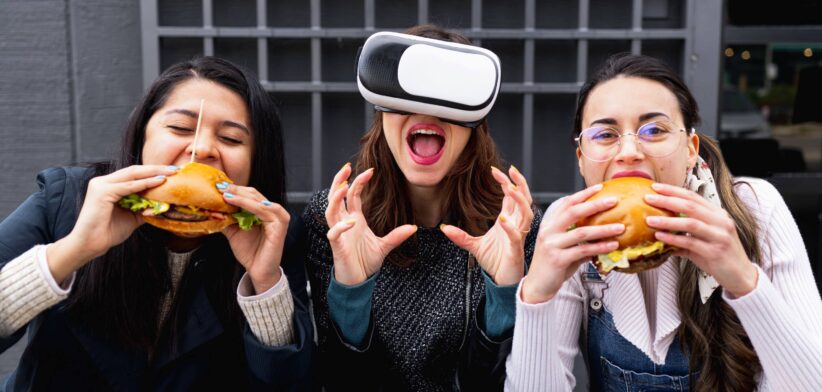 People eating burgers and wearing virtual reality glasses.