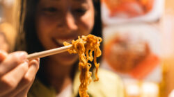 Asian woman enjoy eating noodles street food at night market. Traveler Asian blogger women Happy tourists Beautiful female with Traditional thailand bangkok food.
