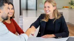 Couple signing papers with another person. \ Newsreel
