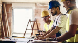 Team of manual workers examining housing project while working at construction site.