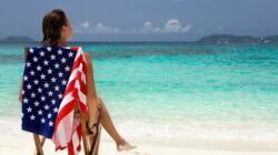 Woman on beach with United States flag beach towel.
