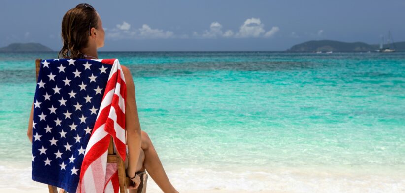 Woman on beach with United States flag beach towel.
