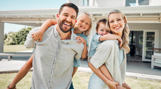 Portrait of a happy carefree caucasian family bonding and relaxing together in the garden or backyard at home. Loving parents carrying their smiling playful son and daughter to enjoy piggyback rides