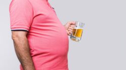 Man with large belly holding a beer. | Newsreel