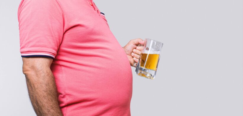 Man with large belly holding a beer. | Newsreel