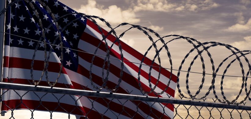 Unites States flag with barbed wire in front.| Newsreel