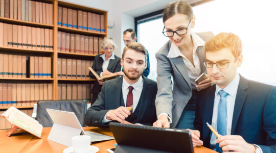 Lawyers in their law firm working on computer with books in background