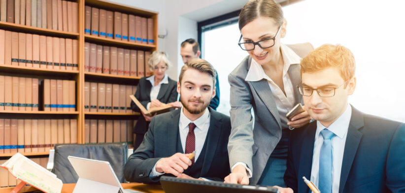 Lawyers in their law firm working on computer with books in background
