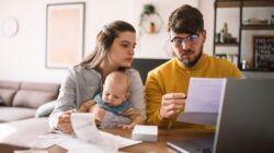 Couple looking at bills with baby. | Newsreel