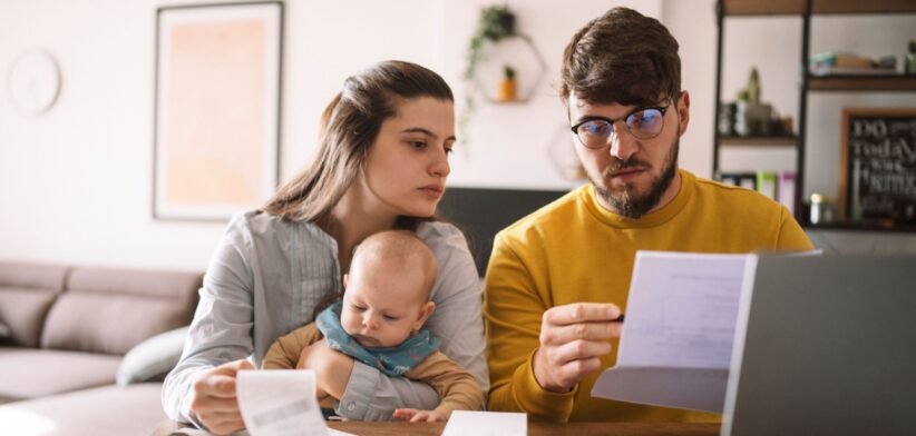 Couple looking at bills with baby. | Newsreel