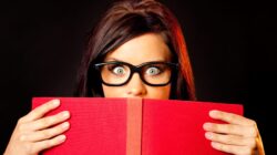 Person peering over book. | Newsreel