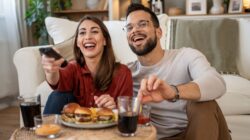 Couple eating takeaways watching TV. | Newsreel