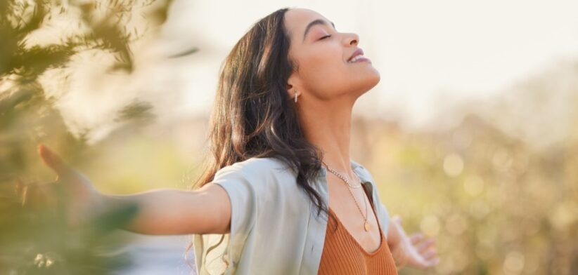 Woman in field facing sun.