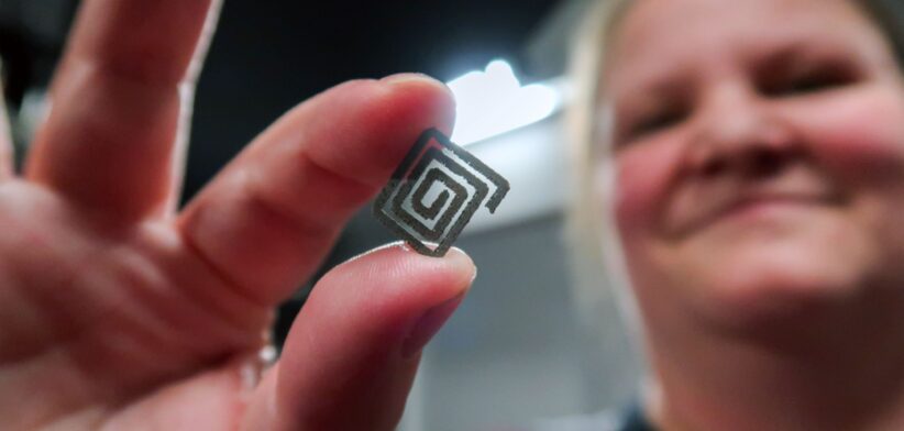 A woman holds a small square spiral-shaped diamond–titanium device between her fingers. | Newsreel